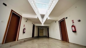 A corridor with a skylight, fire extinguishers, and doors.