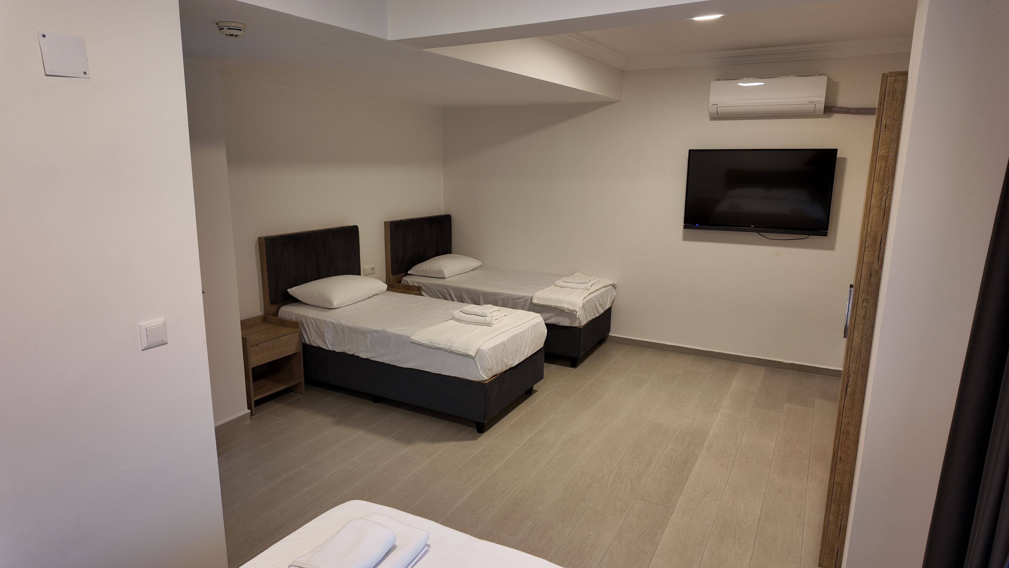 Une chambre d’hôtel moderne équipée de deux lits, d’un téléviseur à écran plat et de la climatisation.