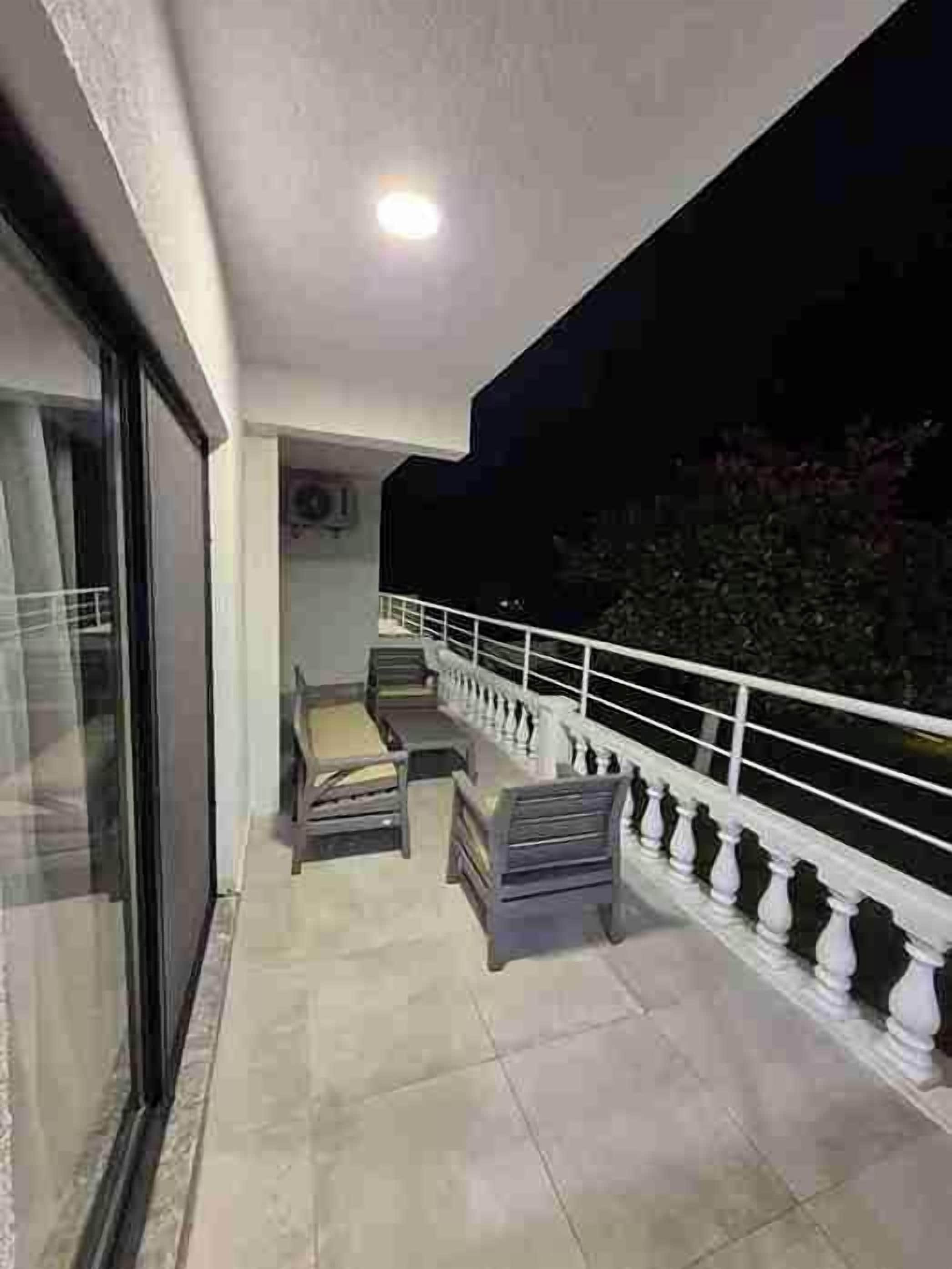 A balcony with a white railing, two chairs, and a table.