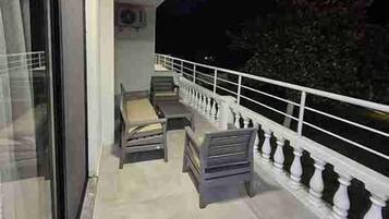 A balcony with a white railing, two chairs, and a table.