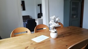 Uma mesa de jantar com cadeiras, um vaso com flores brancas e um pedaço de papel sobre a mesa.