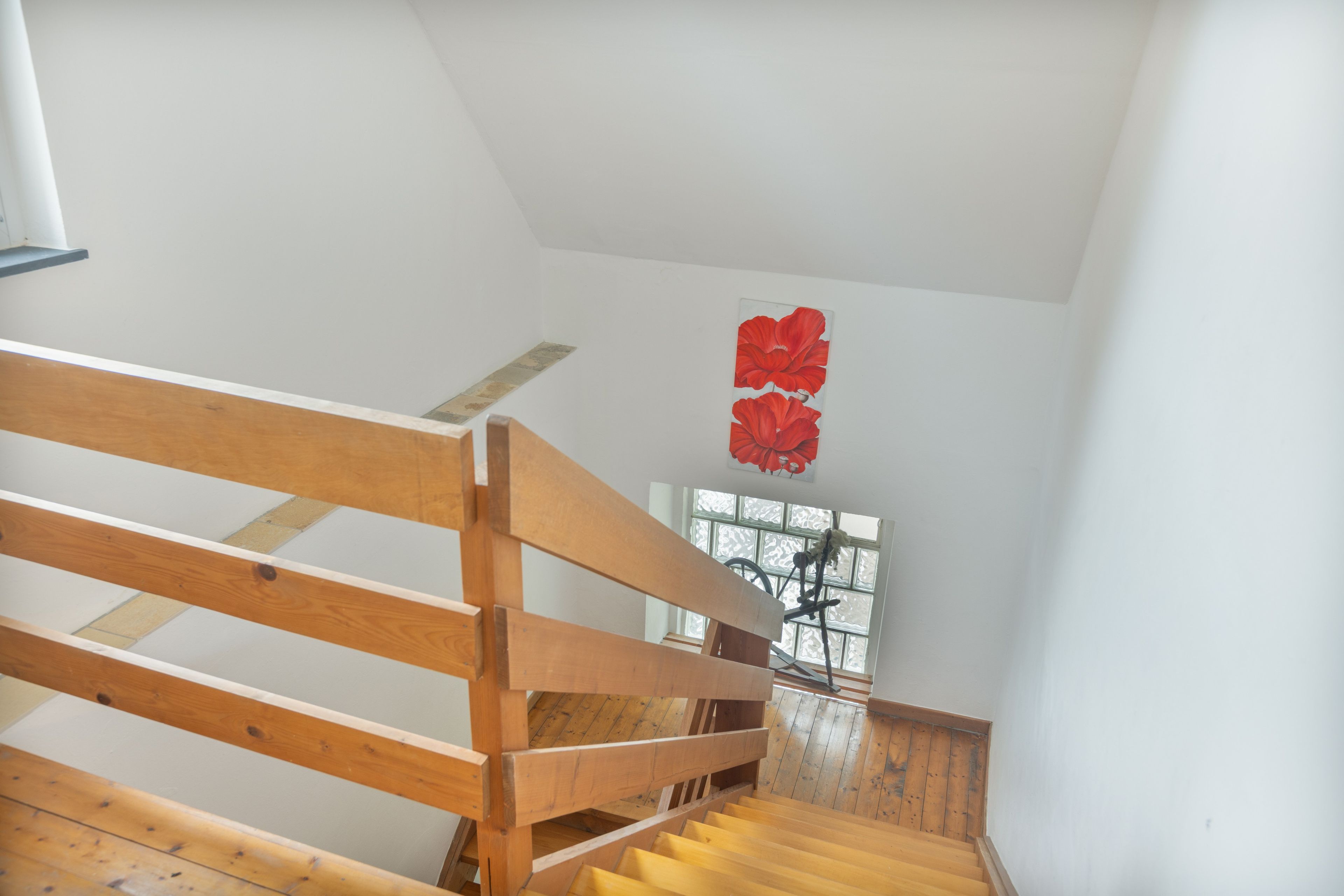 A staircase with wooden handrails leading to a landing with a window.