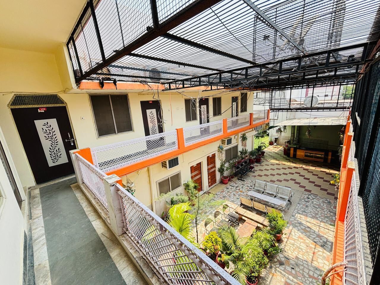 A multi-level outdoor courtyard with a covered seating area, potted plants, and a metal railing.