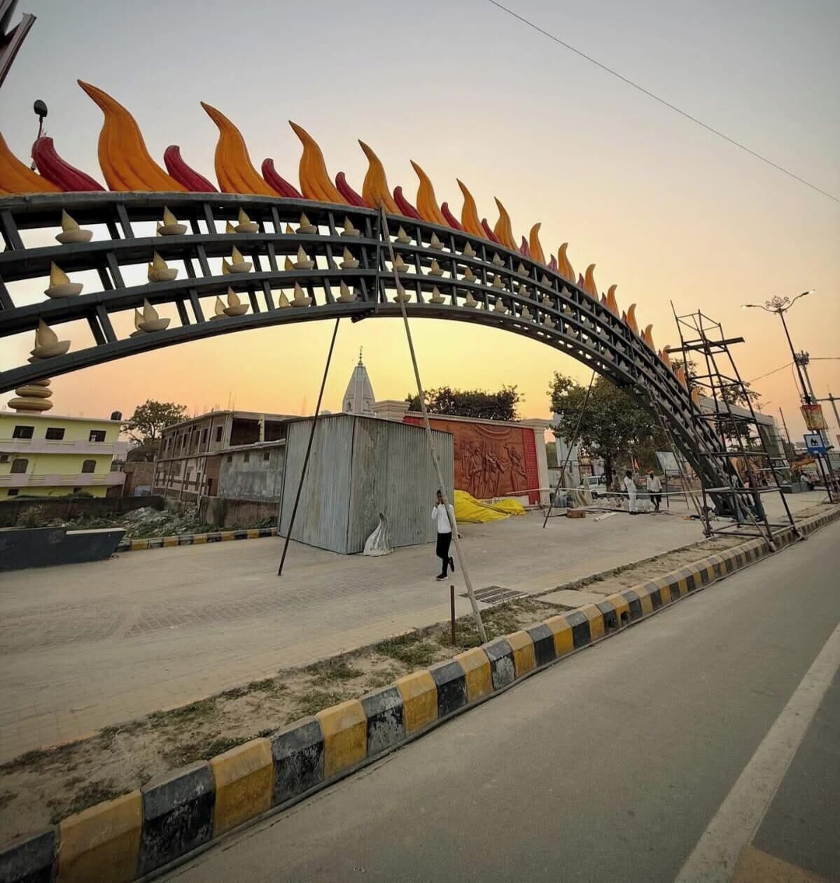 A street with a large decorative archway, a building under construction, and a person walking.