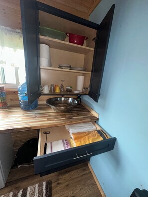 Cocina compacta con encimera de madera, pileta de acero inoxidable y cajón integrado.