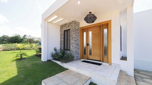 A modern house with a stone facade, a wooden door, and a small garden. - Luxe Villa in the Caribbean • Gated • Pool & Sun (Sosúa)