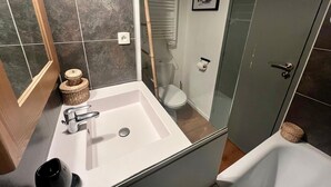 Un bagno con lavandino bianco, water e cabina doccia in vetro.