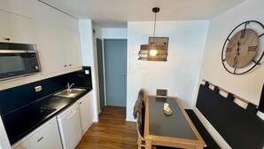 Una cucina compatta con forno a microonde, lavello e zona pranzo con tavolo e sedie.