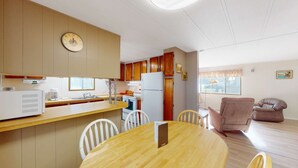 Una cucina compatta con mobili in legno, un frigorifero bianco e un'area pranzo con un tavolo rotondo e sedie.