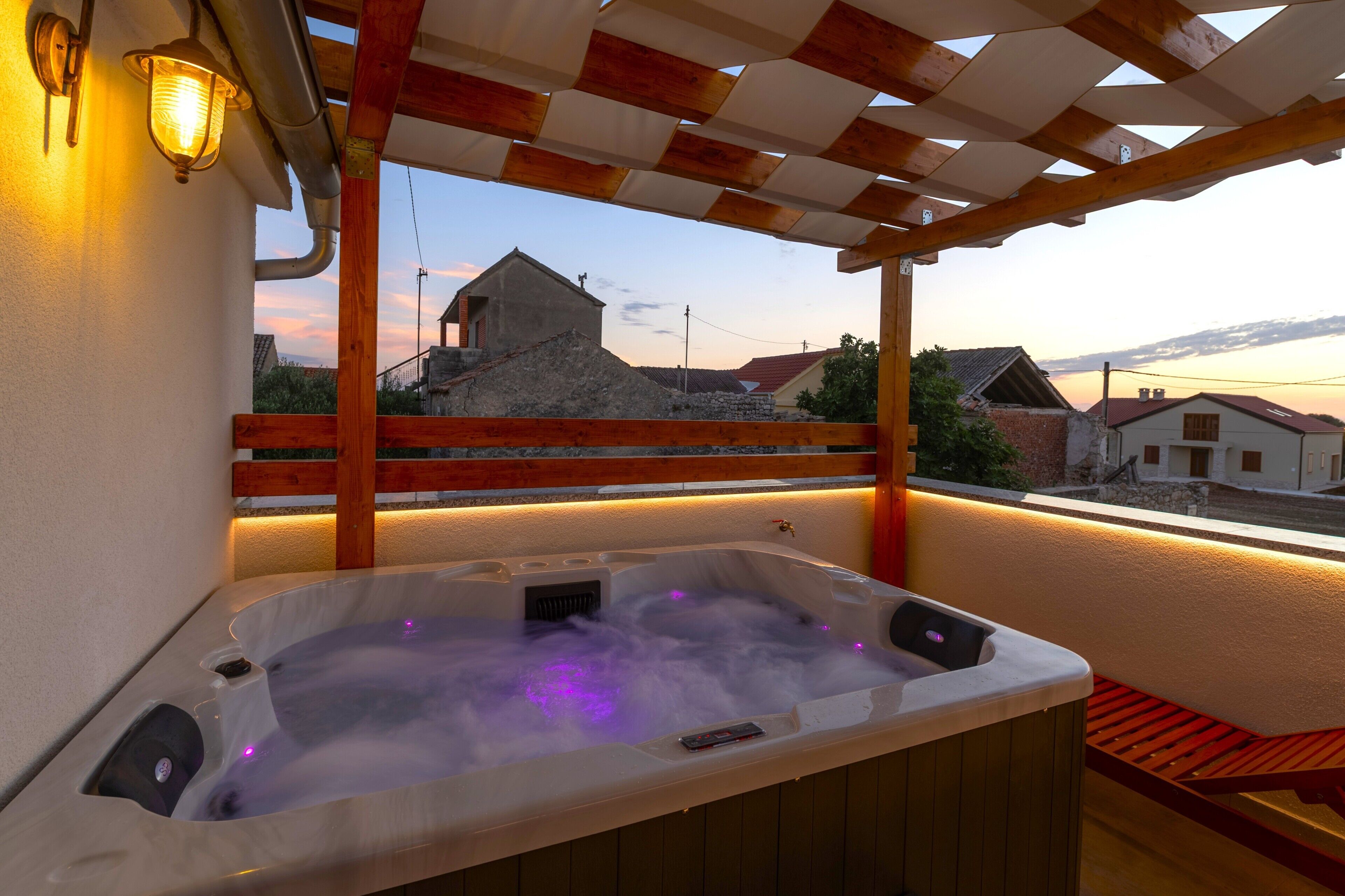 A hot tub with a view of a building and a wooden pergola.