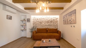 A living room with a sofa, a coffee table, a stone wall, and a painting of birds. - Blažov Dvor (Zaton)