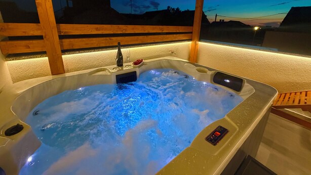 A hot tub with a control panel, a bottle, and glasses on the edge. - Blažov Dvor (Zaton)
