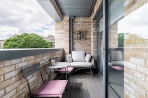 Un balcon avec un mur en briques, une porte vitrée et un espace détente comprenant une table et des chaises.