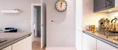 Une cuisine moderne avec une horloge murale, une bouilloire et un support pour bouilloire.