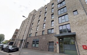 Un immeuble à plusieurs étages, doté d’une façade en briques, de grandes fenêtres et d’un toit plat.
