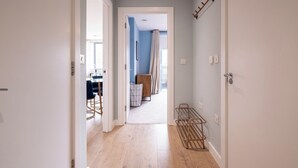 A hallway with a wooden floor, a metal rack, and a door leading to a room with a blue wall and a window. - Contemporary East London Hideaway with Balcony (Greater London)