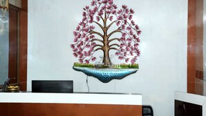 Un mostrador de recepción con un árbol decorativo en la pared y una bicicleta pequeña.