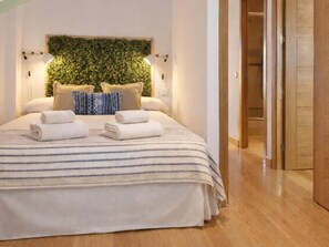 A neatly made bed with striped bedding, two rolled towels, and a green leafy wall decoration. - 8-guest Central Madrid Haven (Madrid)