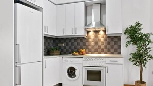 A modern kitchen with white cabinets, a built-in washing machine, an oven, and a stainless steel range hood. - 8-guest Central Madrid Haven (Madrid)