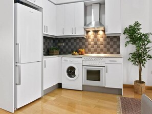 A modern kitchen with white cabinets, a built-in washing machine, an oven, and a stainless steel range hood. - 8-guest Central Madrid Haven (Madrid)