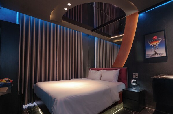 Una habitación de hotel moderna con una cama grande, una mesita de noche y un cuadro en la pared.