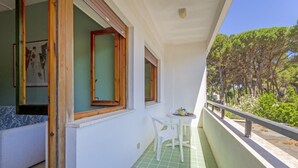 A balcony with a green tiled floor, a white chair, and a small table with a teapot. - A cozy apartment with a balcony that sleeps up to four people, located within the Campoverde Residence in Vernole—set in a Mediterranean pine forest between San Cataldo and the Le Cesine State Nature Reserve. The property is just a short distance from  (Campo Verde)