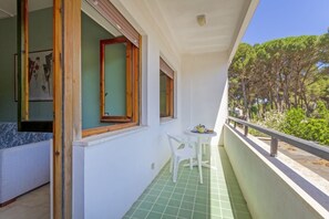 A balcony with a green tiled floor, a white chair, and a small table with a teapot. - A cozy apartment with a balcony that sleeps up to four people, located within the Campoverde Residence in Vernole—set in a Mediterranean pine forest between San Cataldo and the Le Cesine State Nature Reserve. The property is just a short distance from  (Campo Verde)