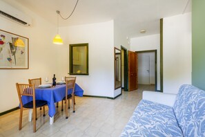 A dining area with a table set for four, a blue sofa, and a mirror on the wall. - A cozy apartment with a balcony that sleeps up to four people, located within the Campoverde Residence in Vernole—set in a Mediterranean pine forest between San Cataldo and the Le Cesine State Nature Reserve. The property is just a short distance from  (Campo Verde)