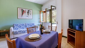 A dining area with a table set for two, a sofa, and a television. - A cozy apartment with a balcony that sleeps up to four people, located within the Campoverde Residence in Vernole—set in a Mediterranean pine forest between San Cataldo and the Le Cesine State Nature Reserve. The property is just a short distance from  (Campo Verde)