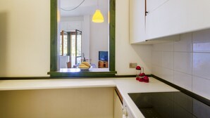 A kitchen with a window, a yellow pendant light, and a red kettle on the counter. - A cozy apartment with a balcony that sleeps up to four people, located within the Campoverde Residence in Vernole—set in a Mediterranean pine forest between San Cataldo and the Le Cesine State Nature Reserve. The property is just a short distance from  (Campo Verde)