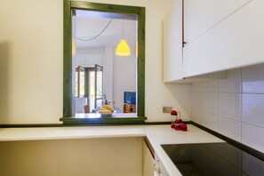 A kitchen with a window, a yellow pendant light, and a red kettle on the counter. - A cozy apartment with a balcony that sleeps up to four people, located within the Campoverde Residence in Vernole—set in a Mediterranean pine forest between San Cataldo and the Le Cesine State Nature Reserve. The property is just a short distance from  (Campo Verde)