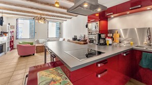 A modern kitchen with a large island, stainless steel appliances, and a red accent wall.