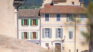 Un edificio con tetto in tegole, un ingresso centrale con una porta e un piccolo balcone con piante in vaso.
