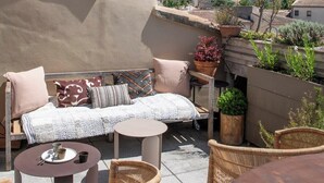 Una terrazza sul tetto con divano, sedie, tavolo e piante in vaso.