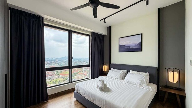 A modern hotel room with a large bed, a ceiling fan, a city view, and a framed picture on the wall.