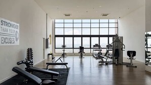 A gym with exercise equipment, a motivational quote on the wall, and large windows with a city view.