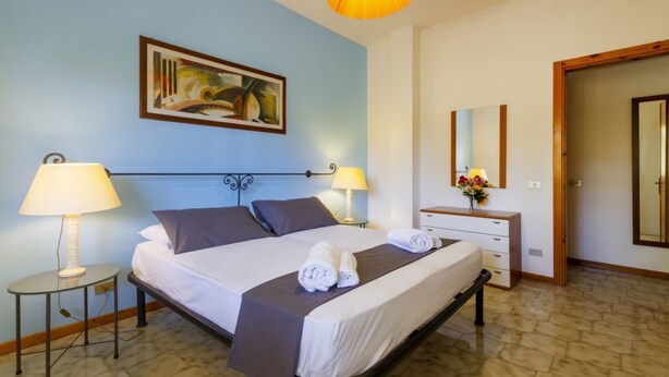A hotel room with a bed, two bedside lamps, a painting on the wall, a dresser, and a mirror. - A delightful apartment with a balcony that sleeps up to four people, located within the Campoverde Residence in Vernole—set in a Mediterranean pine forest between San Cataldo and the Le Cesine Nature Reserve. The property is just a short distance from  (Campo Verde)