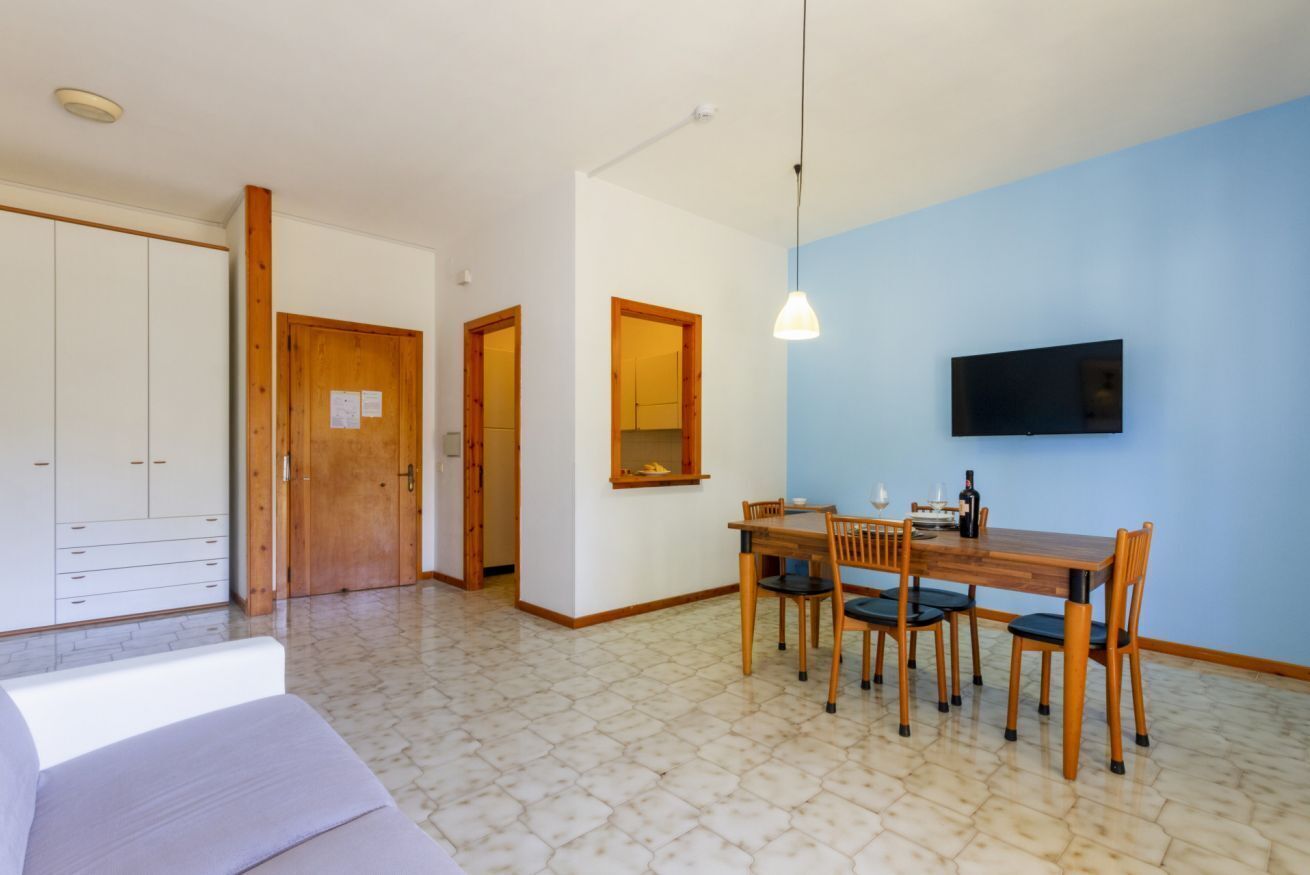 Une pièce comprenant une table à manger, des chaises, un téléviseur fixé au mur et une armoire.