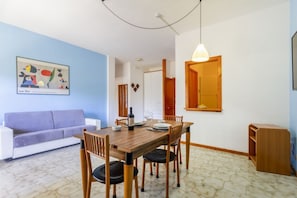 Ein Essbereich mit einem Holztisch, Stühlen, einem weißen Sofa und einem Gemälde an der Wand.