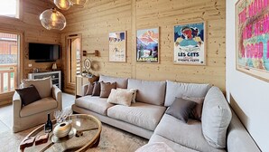 Una sala de estar acogedora con techo de madera, un sofá, una mesa de centro y decoración en las paredes.