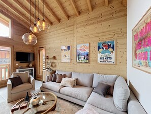 Ein gemütliches Wohnzimmer mit Holzbalkendecke, einer Couch, einem Couchtisch und Wandbildern.