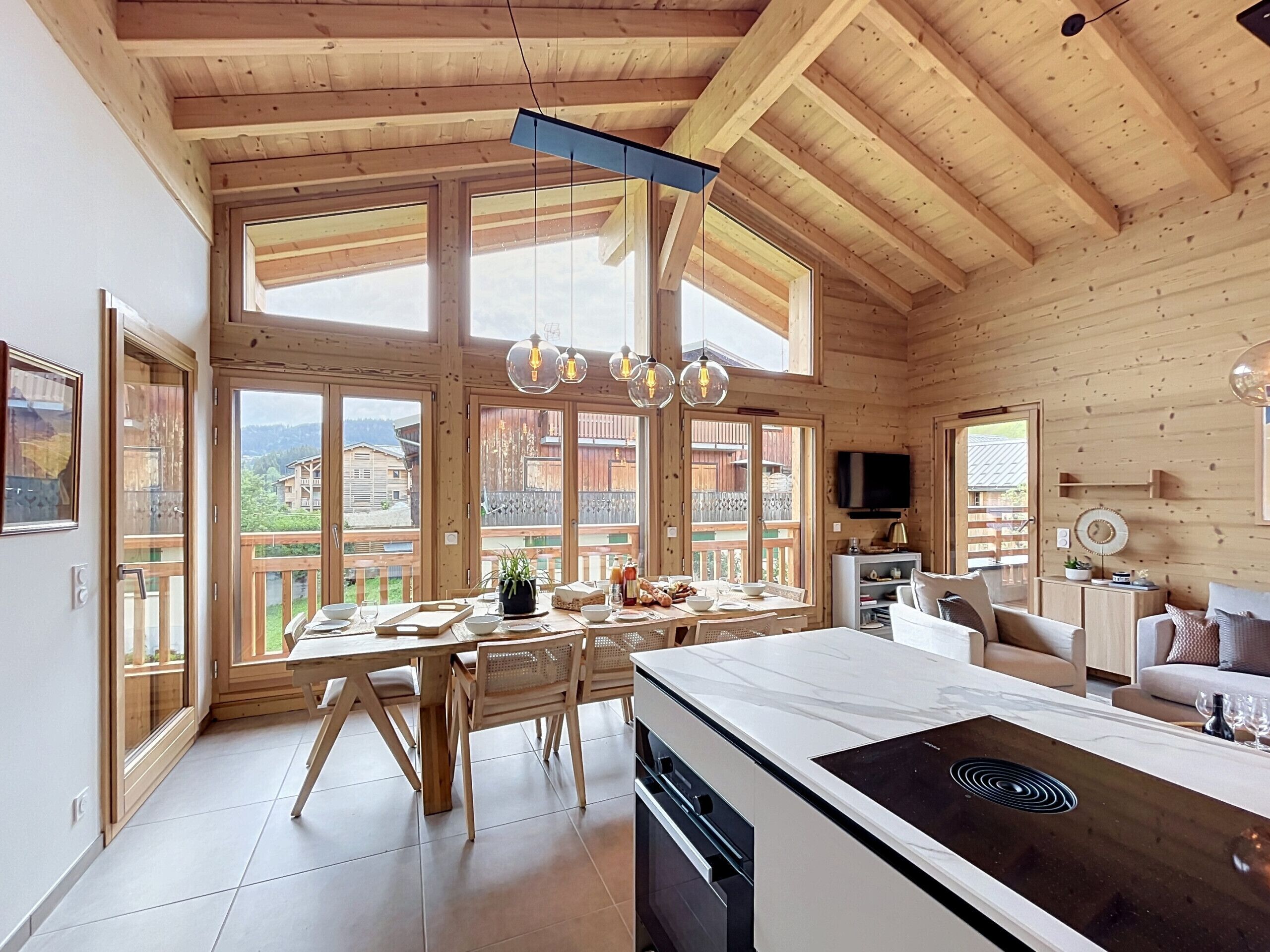 Une cabane en bois comprenant un coin repas, une cuisine et un espace salon.