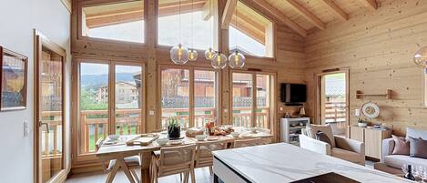 A wooden cabin with a dining area, kitchen, and seating space.