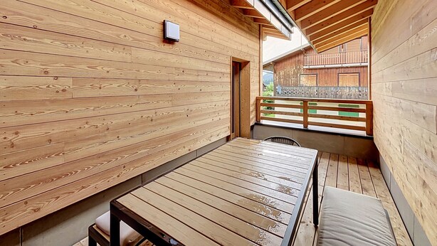 Interior de madera con una mesa, un banco, una ventana con vistas y una barandilla de madera.