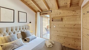 Un dormitorio de cabaña de madera con cama, almohadas, cabecera y ventana.