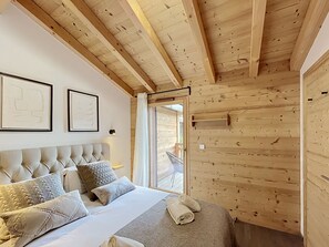 Ein Schlafzimmer einer Holzhütte mit Bett, Kissen, Kopfteil und Fenster.