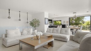 Un salon moderne comprenant un ensemble de canapés, une table basse et un coin repas avec une table et des chaises.