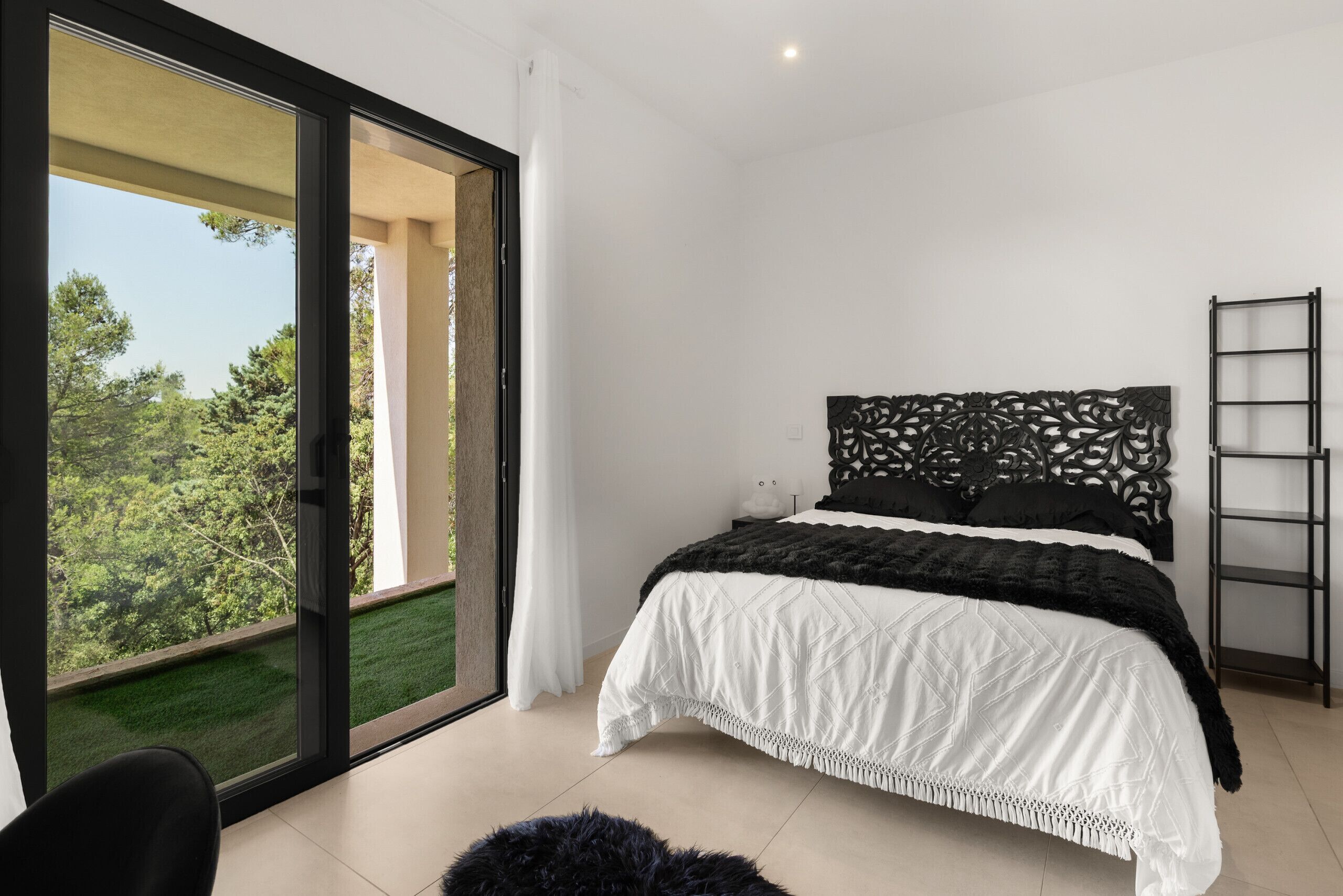 Ein Schlafzimmer mit einem Bett, einer Schiebetür, einem schwarzen Stuhl und einer Leiter.