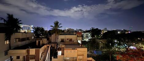 A multi-story residential building with a staircase, balconies, and a view of the surrounding neighborhood at night.