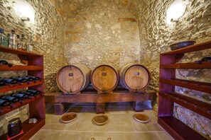 A cellar with wooden barrels, shelves with bottles, and stone walls. - Candice Luxurious Historic Villa, Rentado Vacation Rental Management (Rethymno)